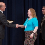 Doctor Potteiger shaking hands with an award recipient in a bright blue shirt